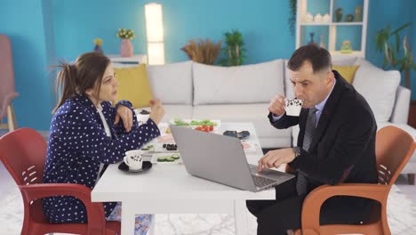 A-workaholic-man-uses-a-laptop-at-the-table-while-having-breakfast-and-his-attention-seeking-wife-gets-angry.